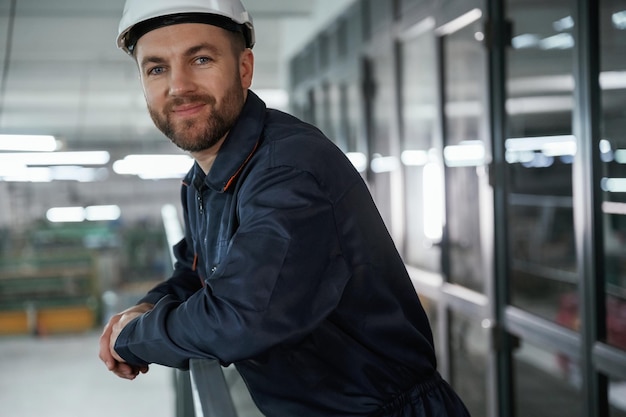 Photo leaning on the railings factory worker is indoors with hard hat