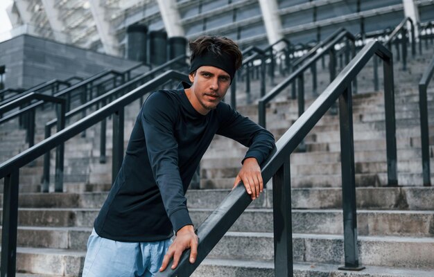 Leaning on railings Young man in sportive clothes have workout outdoors at daytime