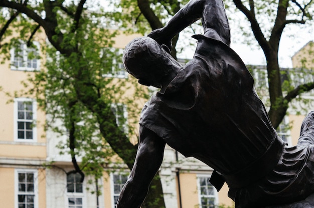 Leaning statue in front of a building seen from behind