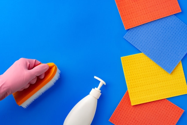 Leaning supplies with hands in rubber gloves on blue background