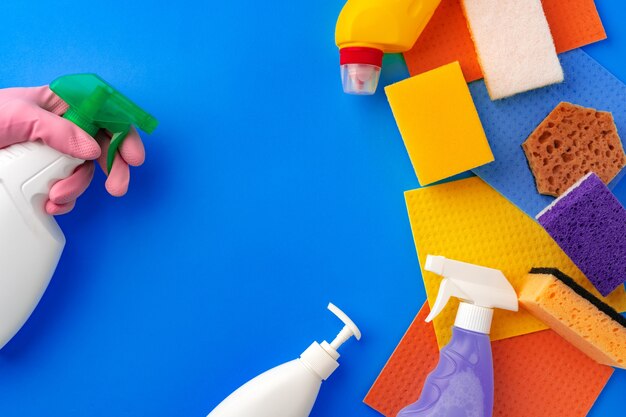 Leaning supplies with hands in rubber gloves on blue background