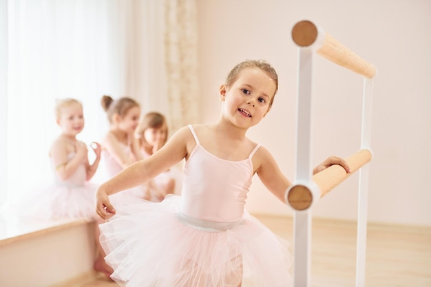 Leaning on the wooden stand Little ballerinas preparing for performance