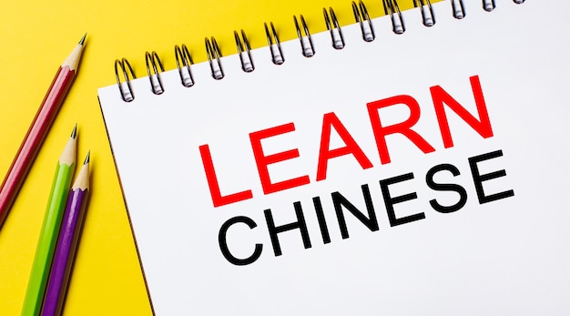 Learn Chinese on a white notepad with pencils on a yellow background