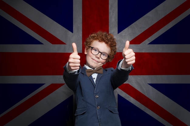 Фото Учитесь английской концепции мальчик-ученик веселится и показывает большой палец на фоне флага великобритании