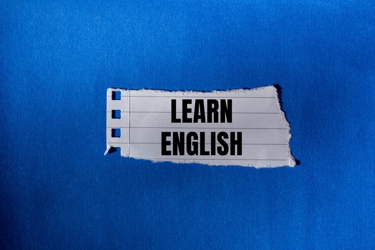 Photo 青い背景の破れた紙に書かれた英語のメッセージを学ぶ 概念的な英語のシンボル コピースペース