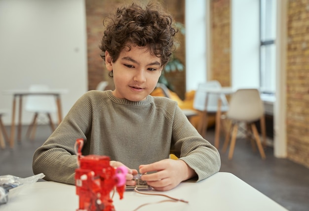 Learn how it works lovely little boy sitting at the table checking technical toy full of details