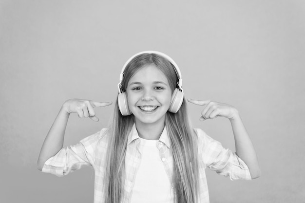 歌の歌詞を学ぶ クリアなサウンド 女児はモダンなヘッドフォンで音楽を聴く 子供の少女は音楽を聴くヘッドフォン 音楽アカウントのプレイリスト 音楽をカスタマイズする ダンスのトラックを聴く