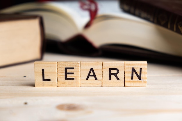 LEARN word written with wooden blocks along with pens glasses and books on a table Study and knowledge concept