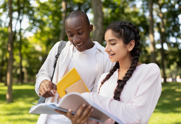 Learning concept multiracial student guy and lady preparing for classes studying with books in