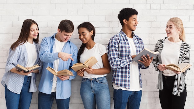 Learning concept Teenagers with books standing near light wall