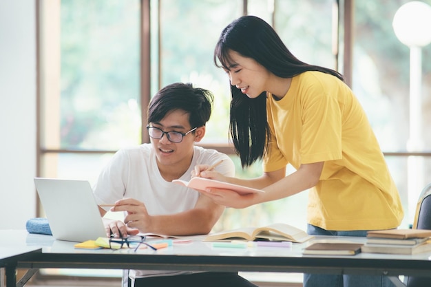 教育と学校の概念を学ぶ若い女性と男性がテストや試験のために勉強している友達と一緒に家庭教師の本若い学生のキャンパスは友達が追いついて学習するのを助けます