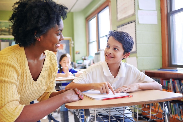 학습 교육 및 교사는 초등학교 교실 지원 장학금 및 행복한 흑인 여성 또는 교육자가 수업 시간에 남성 학습자를 설명하거나 돕는 데 도움을 줍니다.