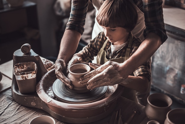 Learning from confident potter. Close-up of confident little boy making ceramic pot on the pottery class