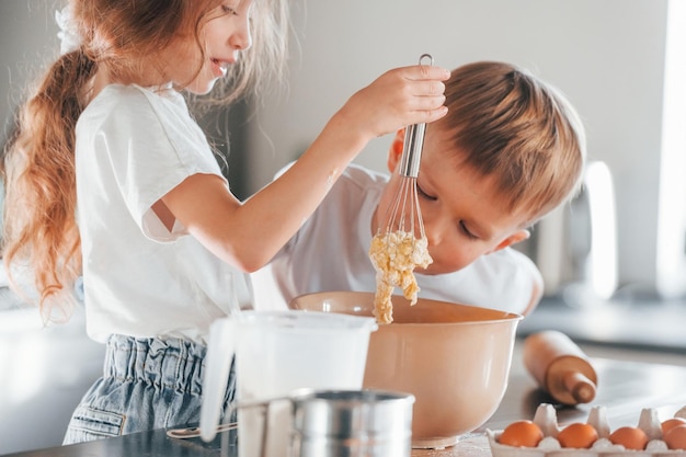 料理の仕方を学ぶ小さな男の子と女の子がキッチンでクリスマス クッキーを準備します。