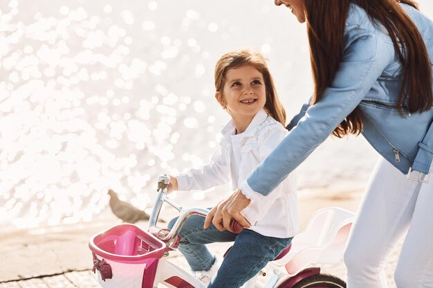 Learning how to drive mother with her young daughter is with
bicycle outdoors together