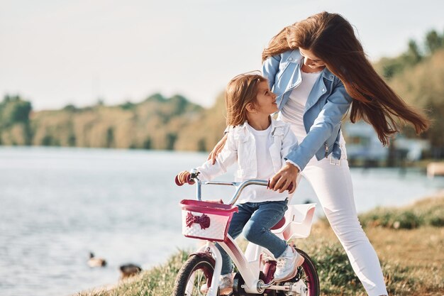 Learning how to drive mother with her young daughter is with
bicycle outdoors together