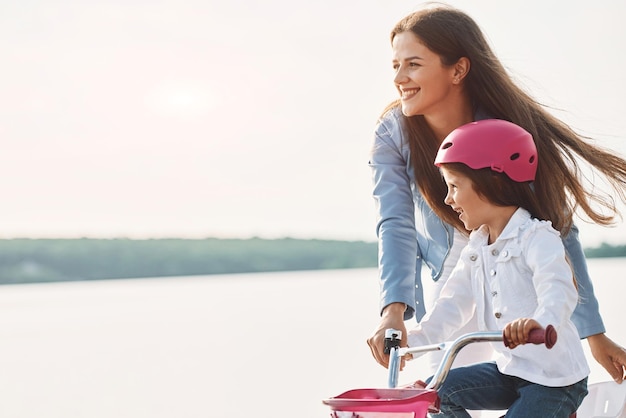 Learning how to drive mother with her young daughter is with
bicycle outdoors together