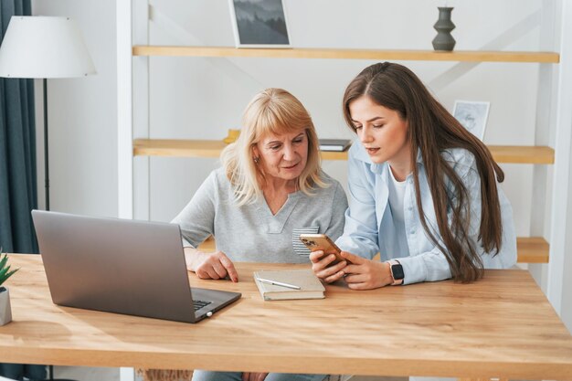 Learning how to use modern technologies Smartphone and laptop Mother and daughter is together at home