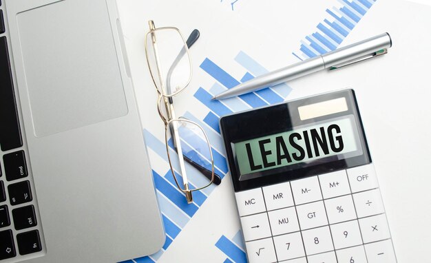 Parola di leasing sulla calcolatrice e occhiali e penna per laptop