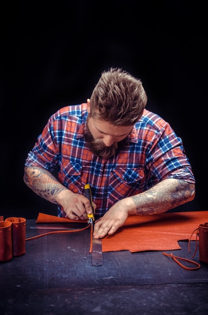 Leather Artist works with leather goods in his tanning shop