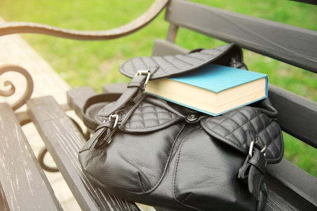 写真 屋外のベンチに本が入った革製のバックパック