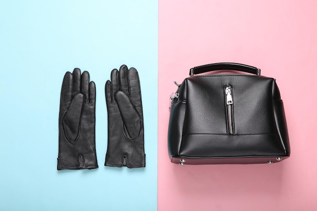 Leather bag and gloves on pink blue background Top view