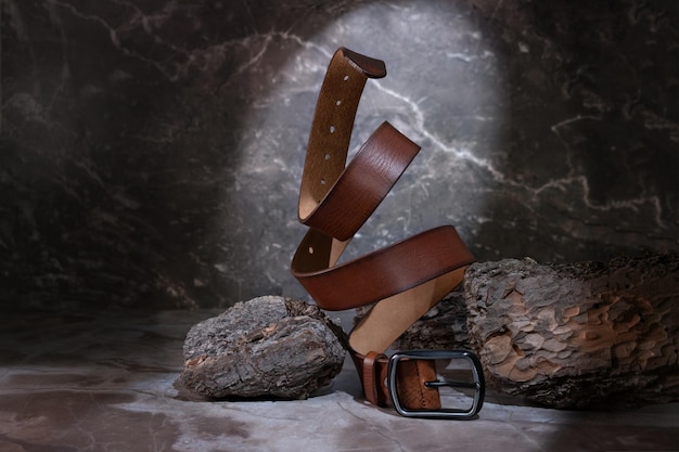 Leather belt on a dark background with bark and natural stone on the background levitation stylish details of men's clothing