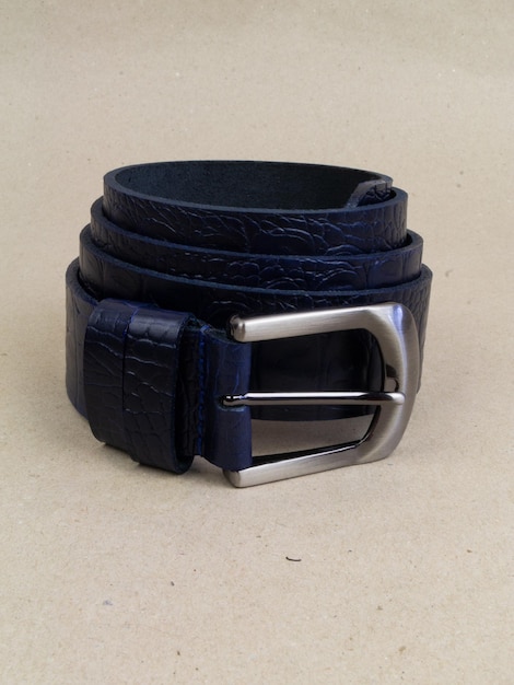 A leather belt with a clasp lies neatly on the table