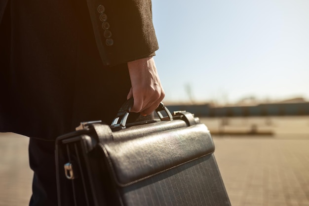 Leather briefcase in his hand young businessman walking on the street