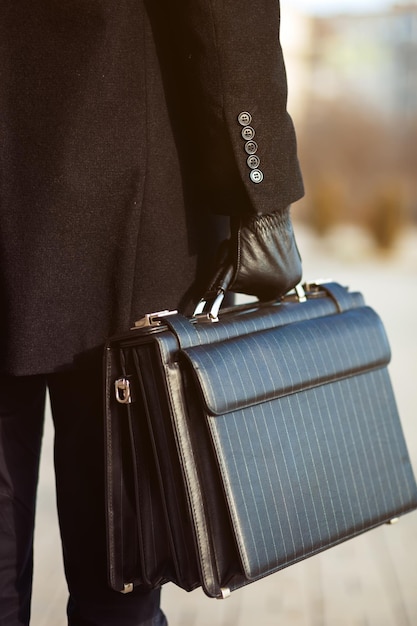 Photo leather briefcase in his hand young businessman walking on the street