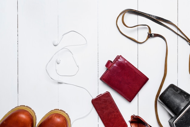 Leather brown purse, old camera, mobile phone in a case and headphones 