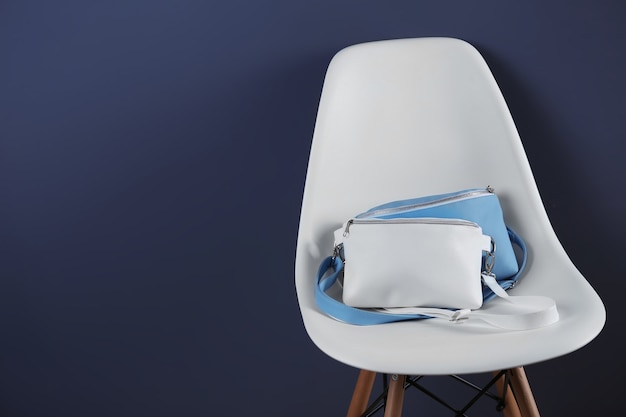 Leather clutches on white chair and dark wall