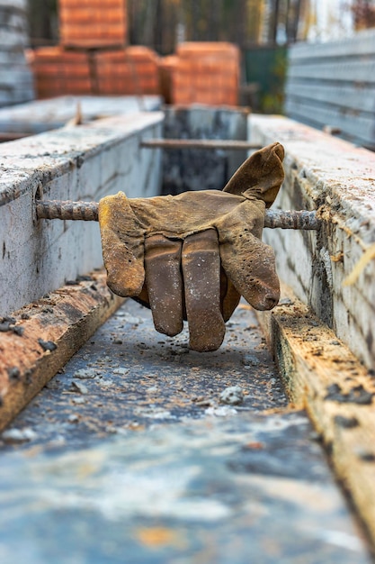 Leather construction gloves on the concrete surface of the foundation Old worker's gloves on a vintage background Remedy of protection