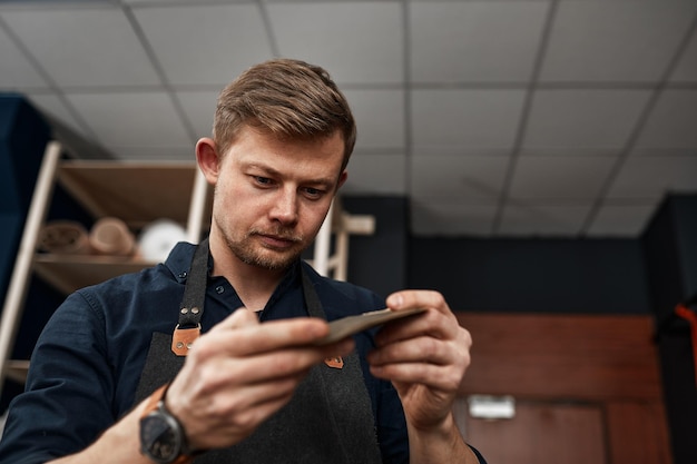 Leather craftsman checks a product in a workshop small and mediumsized businesses a family business for sewing leather goods handicrafts a workshop for finishing and tailoring leather goods