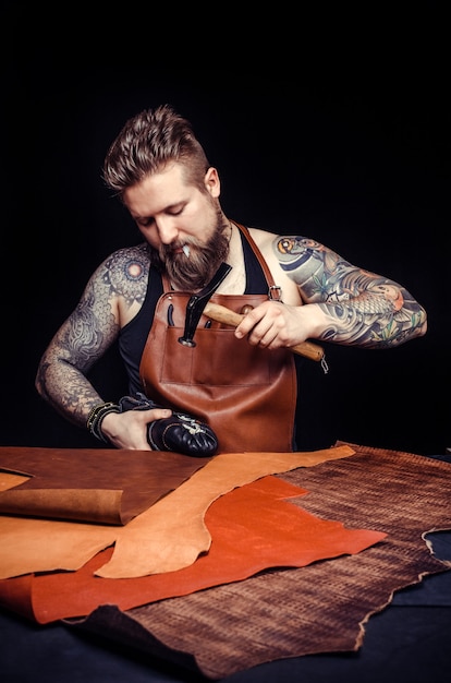 Photo leather craftsman forming new leather production in the tanning shop.