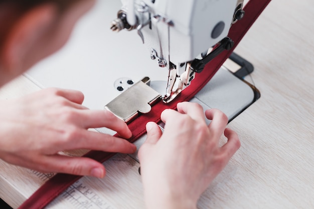 A leather craftsman produces leather goods on a sewing machine in his shop.