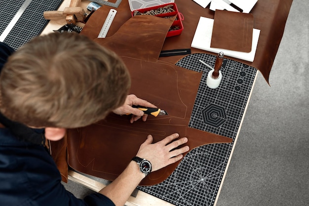 Photo leather craftsmen working making measupenets in patterns at table in workshop studio