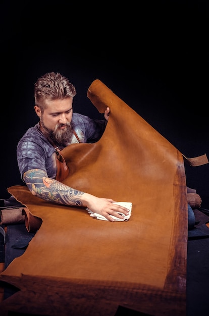 Leather cutter produce a leatherwork in his tanning shop. Tanner of leather producing a leatherwork at workplace.