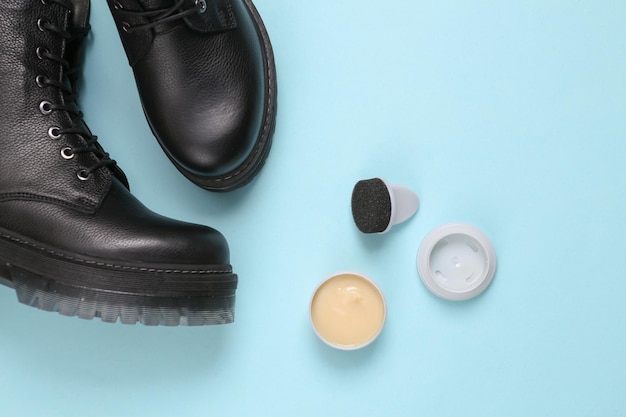 Leather footwear care boots and bottle of shoe polish on blue\
background