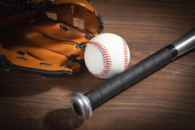 Leather glove with baseball and bat on the wooden background