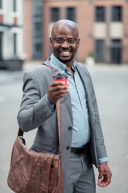 Leather hand bag. Dark-skinned businessman with leather hand bag drinking morning coffee