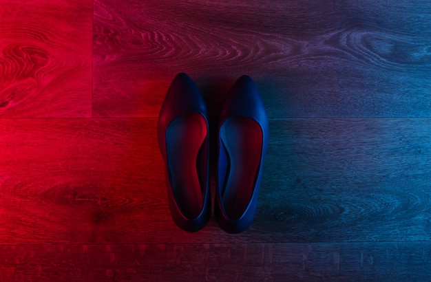 Leather high heel shoes on wooden floor with neon red-blue gradient glow