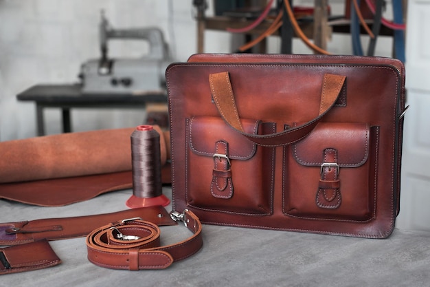 Leather men\'s bag made of genuine leather the photo was created\
in a craft workshop in the background are work tools and a belt\
brown leather briefcase satchel for work