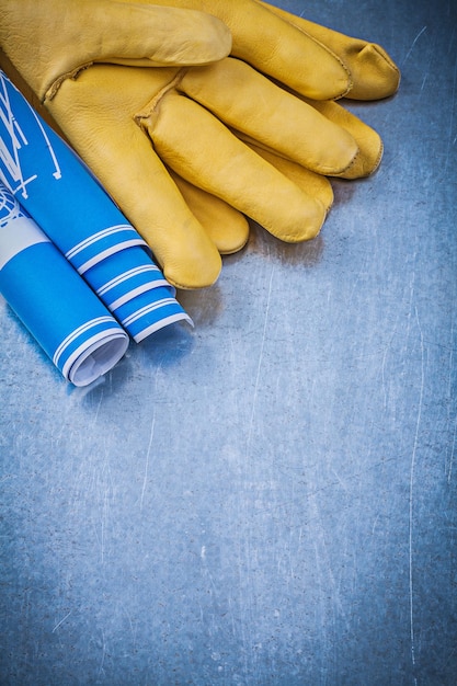 Кожаные защитные перчатки синие скрученные строительные планы на металлическом фоне
