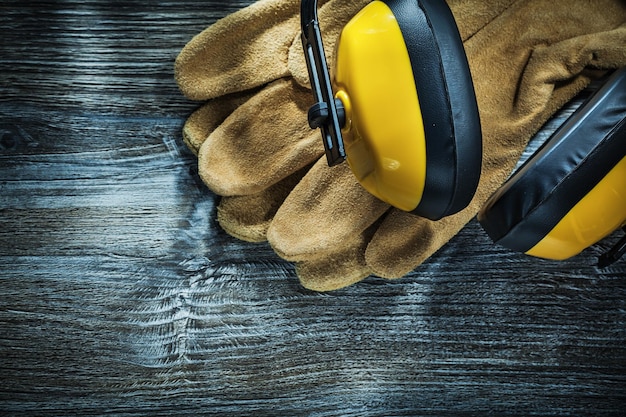 Leather protective gloves earmuffs on wooden board.