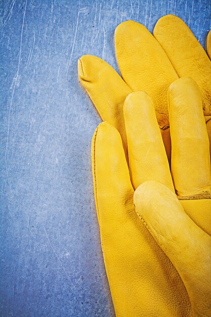 Leather protective gloves on metallic background electricity con