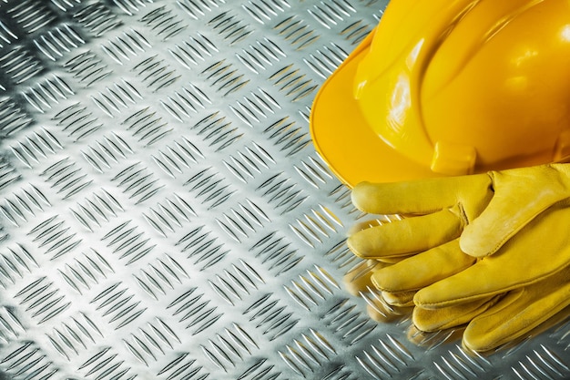 Leather safety gloves hard hat on fluted metal texture