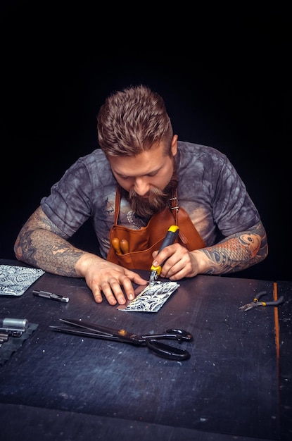 Leather Skinner snijdt leervormen uit voor een nieuw product.