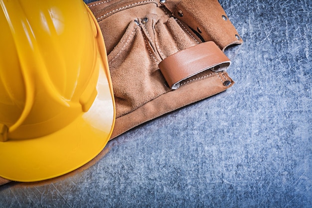 Leather tool belt protective building helmet on metallic background construction concept