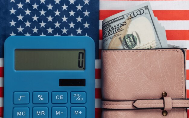 Leather wallet with hundred dollar bills, calculator on of USA flag.